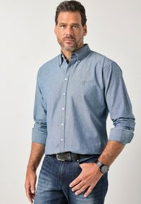 Jasnoniebieska koszula zapinana na guziki, wykonana z denimu, z długimi rękawami podwiniętymi przy mankietach i małym logo na piersi.