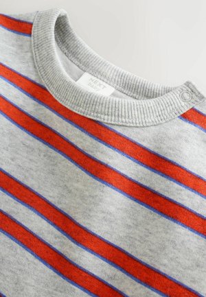 Pilkas ilgomis rankovėmis marškinėlis su raudonų ir mėlynų horizontalių dryžių raštu, ribinėmis apykaklėmis ir sagomis ant peties, kad būtų lengviau apsirengti.