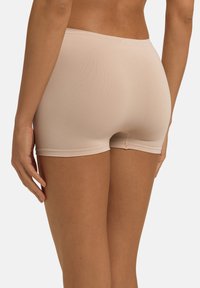 Pantalones cortos beige sin costuras con una textura suave, diseño de cadera baja y tiro corto, con una suave cinturilla elástica y un ajuste aerodinámico.