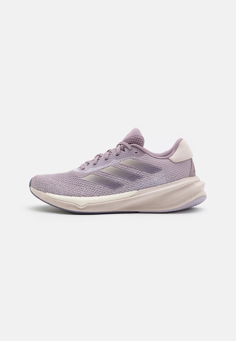 Zapatilla de running de color púrpura claro con parte superior de malla, cuello acolchado y suela texturizada. Presenta franjas sutiles y acentos en blanco roto contrastantes.