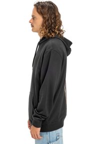 Sudadera negra con capucha y bolsillo canguro, capucha ajustable con cordones y puños acanalados. Presenta un detalle gráfico en la parte posterior.