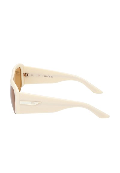 Gafas de sol con un marco de plástico color crema, lentes tintados en marrón y un detalle en dorado en el lateral de las patillas. Diseño angular.