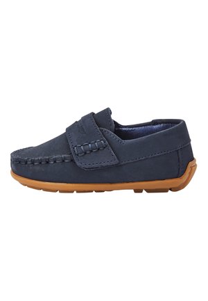 Mocassin bleu marine à enfiler avec détails cousus et semelle en caoutchouc marron, conçu pour une tenue décontractée et un chaussage facile.