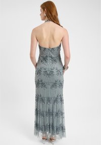 Abito a halter lungo in grigio chiaro. Presenta lavorazioni in perline intricate e ricami floreali, con corpetto aderente e gonna fluida.