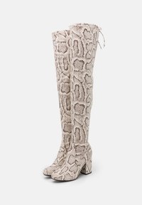 Kniehoge laarzen in gestructureerd nep-slangenprint, met een beige en bruine kleurenpalet, vierkante neus en blokhak met een trekkoorddetail.