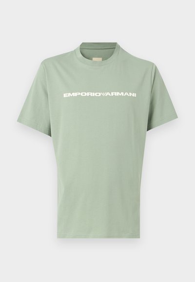 Ανοιχτοπράσινο κοντομάνικο μπλουζάκι με στρογγυλή λαιμόκοψη και λευκό λογότυπο EMPORIO ARMANI στο στήθος, παρουσιάζεται σε απλό φόντο.