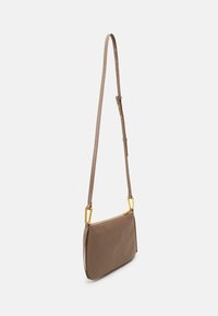 Brun lædertaske med et slankt design. Har en lynlås i guldtonet og en justerbar rem. Glat tekstur med minimalistiske detaljer.