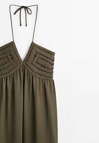 Robe dos nu vert olive avec corsage géométrique en crochet et fines bretelles nouées au cou, jupe en tissu fluide en dessous.