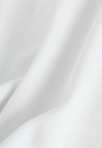 Valge kangas, millel on sile, veidi tekstureeritud pind, millel on peened lained ja voldid. Ühtlaselt värvitud, ilma nähtavate mustrite või aktsentideta.