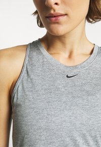 Grå atletisk tanktop med en tekstureret overflade og rund halsudskæring. Har en lille sort Nike-logo på brystet.