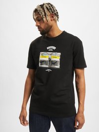 Sort bomulds T-shirt med et grafisk print af en bodega facade med gule akcenter, der viser ordene "Hjørne" og "Butik."