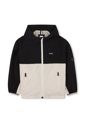 Capuchonjack met een zwart bovenstuk en een crèmekleurig onderstuk, voorzien van ritszakken, elastische manchetten en een logo op de borst.