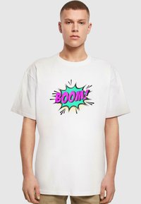 Camiseta de algodón blanca con un gráfico colorido de "¡BOOM!" con un diseño de explosión de estrellas. Mangas cortas y un corte relajado.