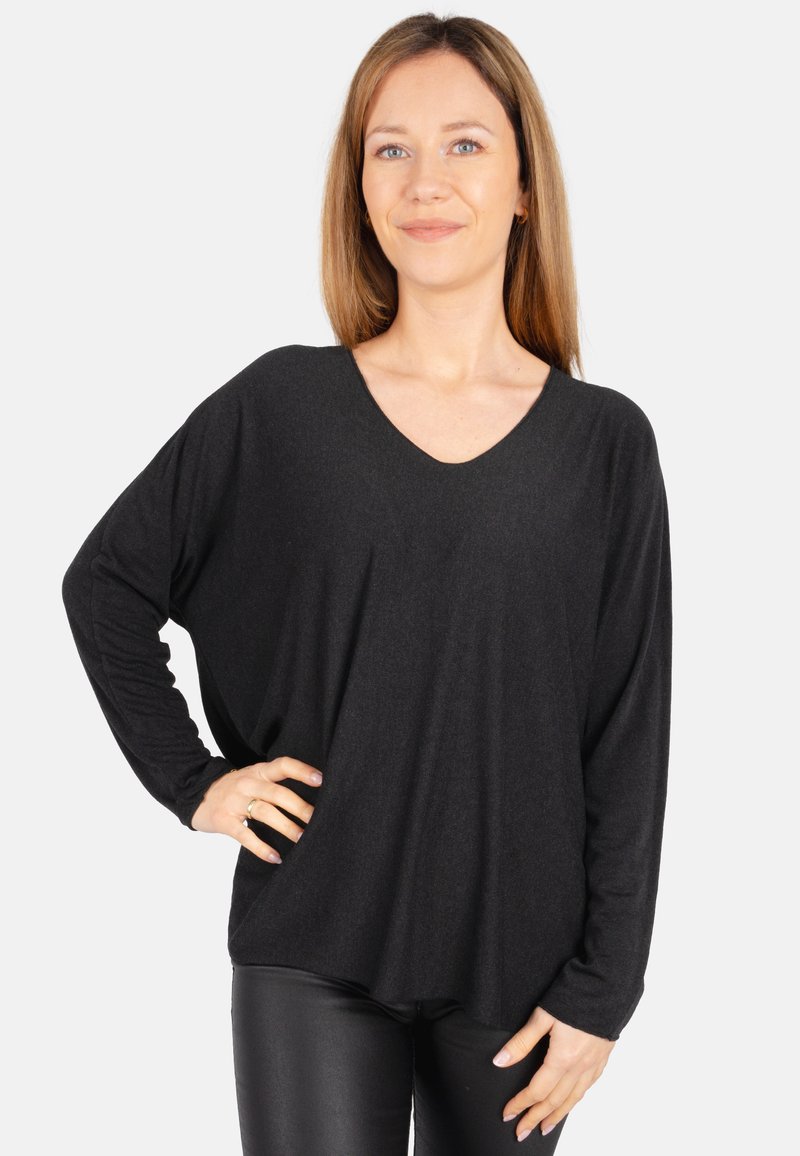 Schwarzes, langärmliges Oberteil mit einem weiten V-Ausschnitt, drapiertem Schnitt und weicher Textur, kombiniert mit eng anliegenden schwarzen Hosen. Schlichtes, lässiges Design.