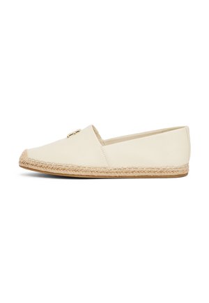 Beige slip-on espadrille sko med vævet reb-sål og lille guldfarvet metal detalje på overdelen, vist i sidelignende profil på hvid baggrund.