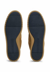 Schuhsohlen mit einer strukturierten navyblauen Gummisohle und einem oberen Teil aus beige Wildleder, ausgestattet mit einem Logo-Abdruck und kontrastierenden Rillenmustern.