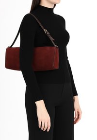 Bordeaux kleurige suède handtas met een rechthoekige vorm, aangevuld met een verstelbare bruine schouderriem en contrasterende stiksels.