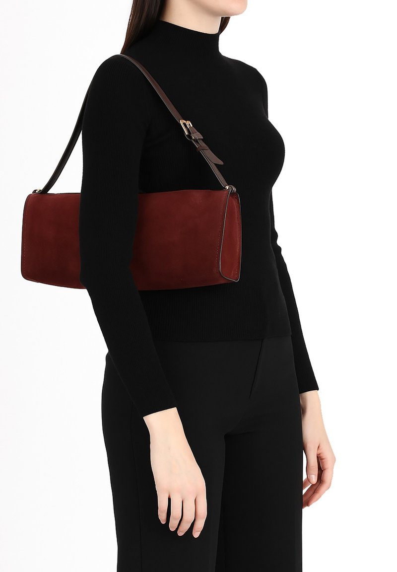 Bordeaux kleurige suède handtas met een rechthoekige vorm, aangevuld met een verstelbare bruine schouderriem en contrasterende stiksels.