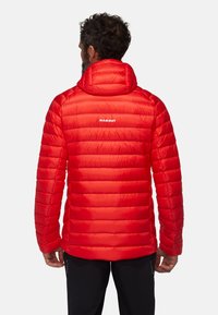 Giacca rossa a vento con cappuccio, caratterizzata da un'imbottitura orizzontale e un piccolo logo bianco sul retro. Tessuto liscio e lucido con una silhouette aderente.