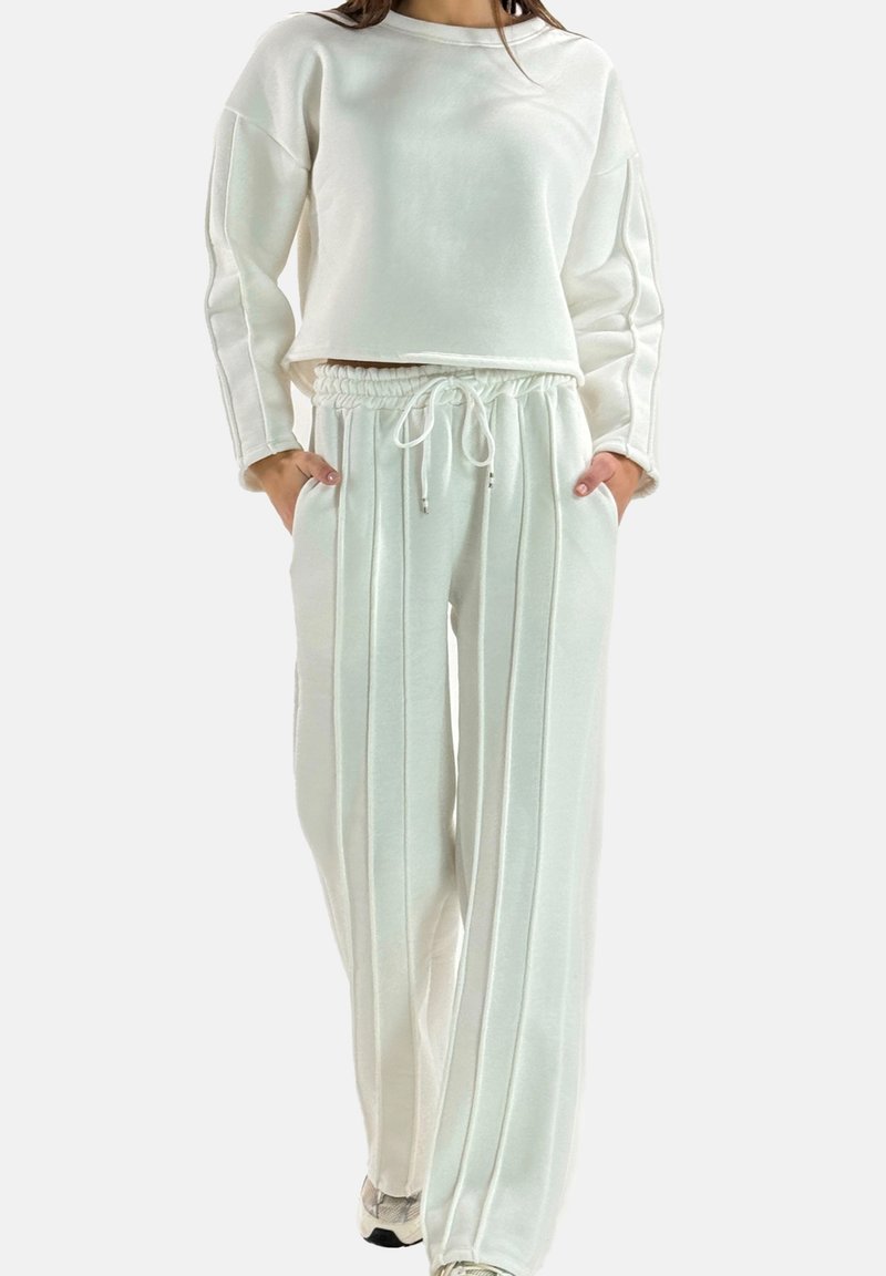 Sweat-shirt ample de couleur claire avec épaules tombantes, associé à un pantalon large assorti avec une taille à cordon et des rayures verticales.