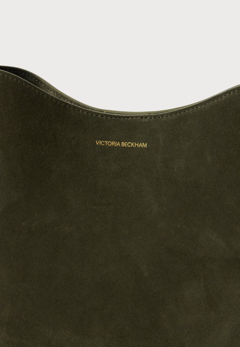 Bolso de ante verde oliva con una textura suave y una parte superior curva. Presenta un texto dorado en relieve que dice "VICTORIA BECKHAM" en el lateral.