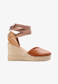 Brune læder wedge espadrille med vævet jute sål, der har en struktureret overdel og et mønstret ankelrem til sikker lukning.