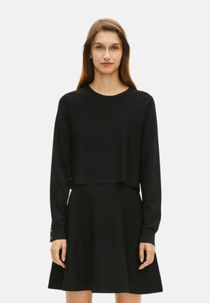 Abito lungo nero a maniche lunghe con top corto, gonna svasata e dettagli con bottoni dorati sui polsini, caratterizzato da una texture liscia.
