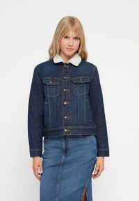 Giacca di jeans con collo in finta pelliccia, realizzata in tessuto blu scuro, apertura con bottoni, due tasche sul petto e tasche laterali, design corto.
