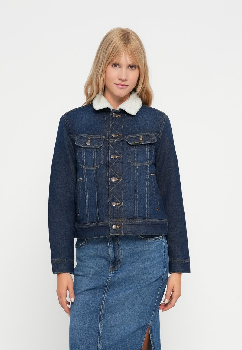 Giacca di jeans con collo in finta pelliccia, realizzata in tessuto blu scuro, apertura con bottoni, due tasche sul petto e tasche laterali, design corto.