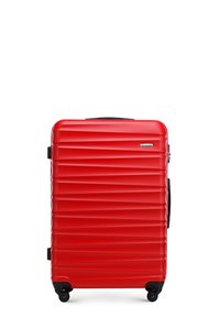 Valise rigide rouge avec des rainures horizontales, accents noirs et quatre roues. Équipée d'une poignée télescopique et d'un cadenas à combinaison.