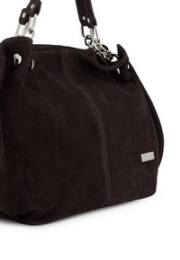 Donkerbruin suède handtas met een afgeronde vorm, zilveren hardware accenten en een merkplaat. Beschikt over een zachte textuur en structurele naden.