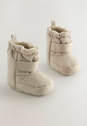 Beige, gesteppte Babystiefel mit weicher Innenausstattung, elastischem Oberteil und verstellbarem Klettverschluss; runde Zehenpartie und strukturierte Sohle für besseren Halt.