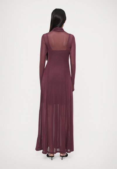 Abito in chiffon malva con maniche lunghe, collo alto e schiena trasparente. Presenta un corpino aderente e una gonna fluida, con spacchi laterali.