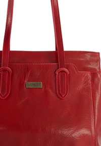 Czerwona skórzana torba tote o gładkiej fakturze, z podwójnymi uchwytami i przeszyciami. Posiada prostokątny kształt oraz płytkę z logotypem marki.
