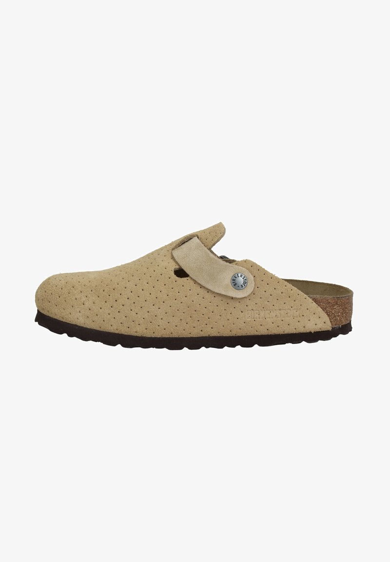 Beige Wildleder-Slipper mit durchbrochenem Design, Korkfußbett, verstellbarem Riemen und dunkler Gummisohle. Mit einem Metalllogo-Akzent.
