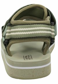Green sandal with a textured upper, featuring striped straps and a cushioned footbed. Solid rubber sole with a light-colored edge.