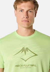 Maglietta a maniche corte verde brillante con un grafico di montagna in verde scuro e la scritta "ASICS FUJITRAIL" stampata sotto. Tessuto morbido.