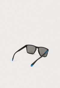 Mustat suorakaiteen muotoiset aurinkolasit tummilla linsseillä ja sinisillä päillä, esitettyinä vaaleaa taustaa vasten.