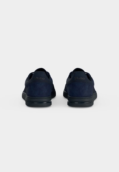 Ζευγάρι σκούρα μπλε sneakers Polo, εμφανιζόμενα από πίσω σε απλό ανοιχτό φόντο.