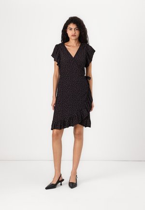 Robe noire à motifs floraux, avec des manches courtes à volants et un ourlet à volants, dotée d'un détail de lien à la taille. Portée avec des escarpins noirs à brides arrière.