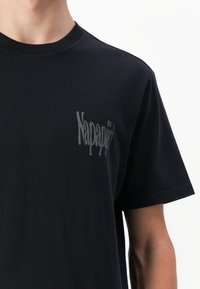 Sort bomulds T-shirt med korte ærmer, der har et tekstureret logo trykt i grå på venstre brystområde. Enkel rund halsudskæring.