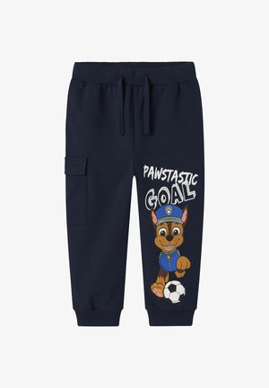 Pantalones de chándal azul marino hechos de una mezcla de algodón, con una ilustración de un perro de dibujos animados en un uniforme azul y el texto "OBJETIVO PAWSTÁSTICO".