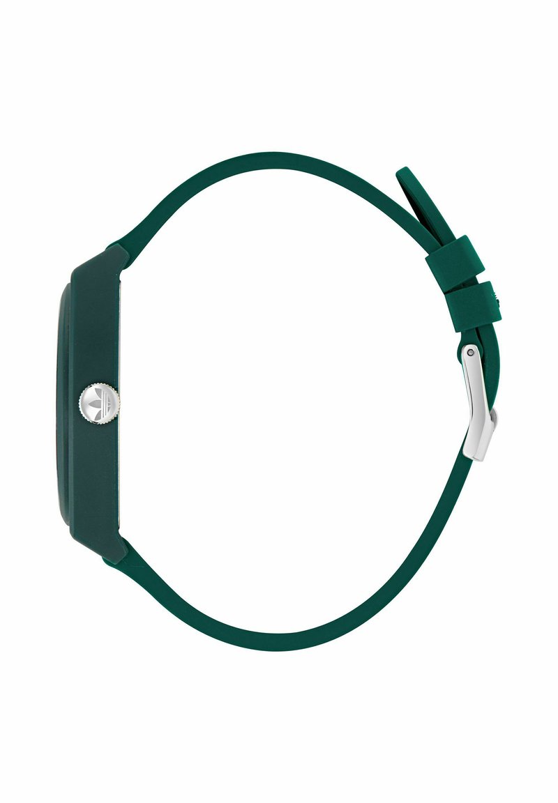 Reloj de pulsera verde oscuro con correa de silicona, vista lateral que muestra la corona plateada con el logotipo de Adidas y el cierre de hebilla metálica sobre fondo blanco.