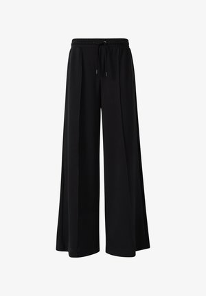 Schwarze weit geschnittene Hosen aus weichem Stoff, mit einem elastischen Bund und einer Kordel, sowie Falten im Vorderteil.