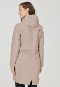 Beige vandtæt jakke med hætte, elastiske manchetter, bagventilation og bælte i taljen. Lavet af glat, letvægtsmateriale.