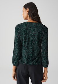 Blusa nera e verde petrolio con motivo, maniche lunghe, scollatura tonda e dettaglio dell'orlo arricciato, realizzata in tessuto leggero.