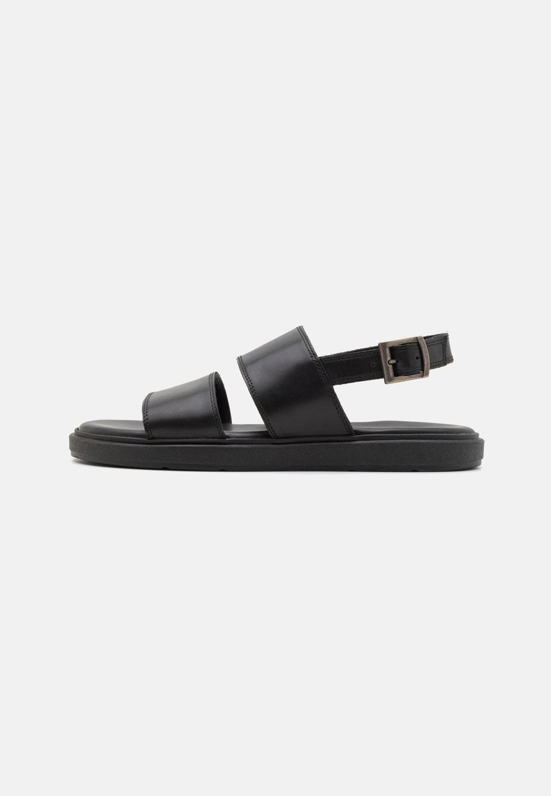 Sorte lærsandaler med to brede remmer, spænde lukning og flad gummisål. Glat tekstur, minimalistisk design og åben bag.