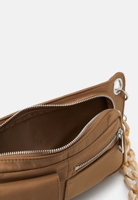 Brun stof tas med to lynlåsede rum; har en blank kædetræk og metaløje detalje. Indvendig foret med matchende stof.