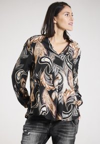 Schwarze Bluse mit einem Paisley-Muster in Beige, Braun und Grau. Sie hat einen V-Ausschnitt und lange Ärmel und besteht aus einem glatten, weichen Stoff.