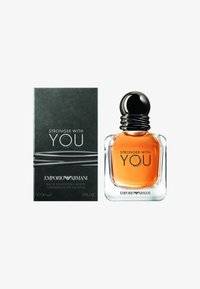 Eau de toilette i en klar glassflaske med en amber væske, toppet med en svart spiralhette; pakket i en mørkegrønn boks med sølvdetaljer.